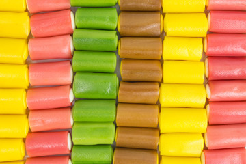 background of gummy rolls in yellow, pink, green and brown