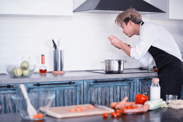 Asian cook in the kitchen prepares food in a cook suit
