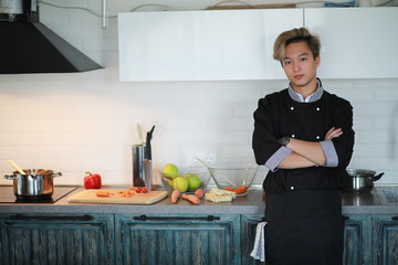 Asian cook in the kitchen prepares food in a cook suit