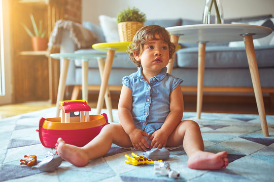 Beautiful toddler child girl sitting on the carpet playing with smartphone