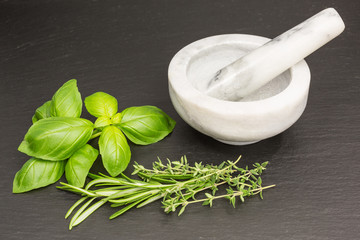 basil, rosemary and thyme with white and grey marble mortar and pestle