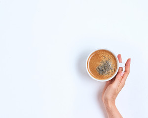 Fototapeta premium White coffee cup in female hands on a white background. Top view