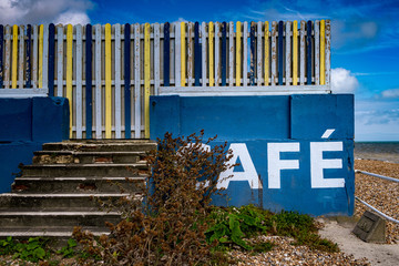 Blue beach cafe sign with multicoloured fence