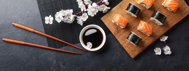 Set of sushi and maki rolls with branch of white flowers on stone table - Powered by Adobe