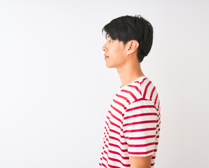 Young chinese man wearing casual striped t-shirt standing over isolated white background looking to...