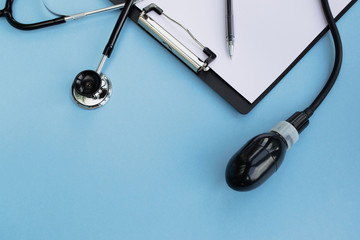 Healthcare and medical concept. Medical stethoscope, blood pressure meter, blank clipboard and pen on a light blue background. Copy space