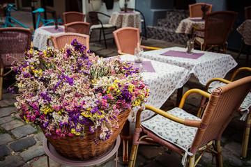 Fototapeta na wymiar Bucket with flowers in outdoor cafe in Lviv