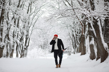 A man on a walk in the park. Young man with in the winter snowfall.