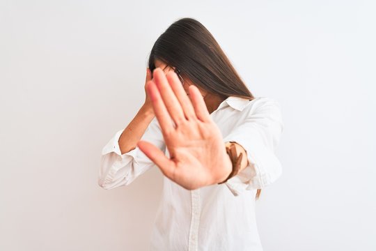 Young beautiful businesswoman wearing glasses standing over isolated white background covering eyes with hands and doing stop gesture with sad and fear expression. Embarrassed and negative concept.