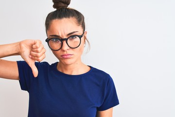 Beautiful woman with bun wearing blue t-shirt and glasses over isolated white background with angry...