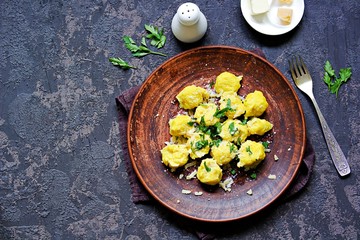 Pumpkin dumplings or gnocchi with parmesan cheese, butter and parsley on a brown clay plate. Harvest pumpkins. Thanksgiving Day. Top view, copy space. Italian food.