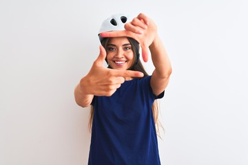 Young beautiful cyclist woman wearing security bike helmet over isolated white background smiling making frame with hands and fingers with happy face. Creativity and photography concept.