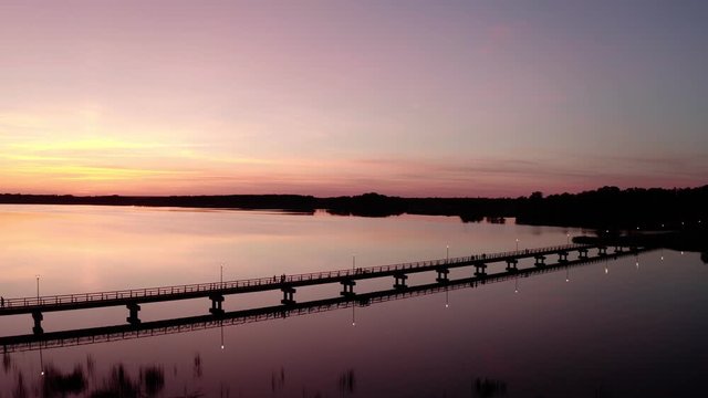 Drone Flight at Sunset by the lake Sirvena in Birzai - the longest wooden bridge in Lithuania.The bridge is located in Regional Park, connecting Birzai with Astravas Manor on the northern edge of the