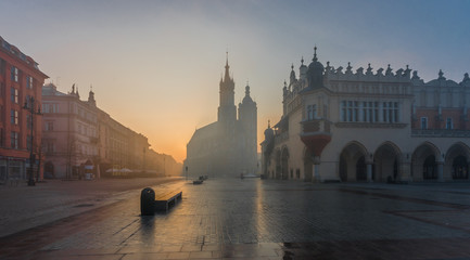 Krakow, Poland, St Mary's church and Sukiennice (Cloth hall) on the Main Square in morning fog illuminated by rising sun