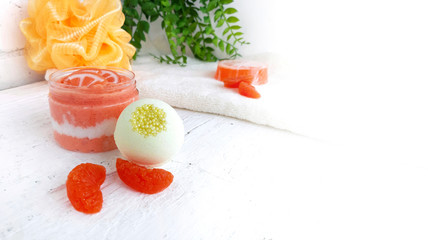 Orange sugar scrub with spa bomb and tangerine on white wooden background.Mock up image of anti...