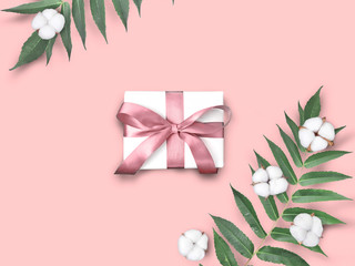 Gift box  with cotton flowers and leaves on pink background. Greeting holiday concept for Valentines day, Mothers day, Womans day or wedding celebration.