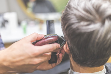 Barbershop. Hairdresser does hairstyle with hair clipper and comb.
