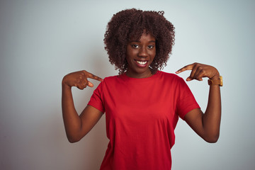 Young african afro woman wearing red t-shirt over isolated white background looking confident with smile on face, pointing oneself with fingers proud and happy.