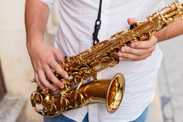 Close up of a man holding his saxophone on the street