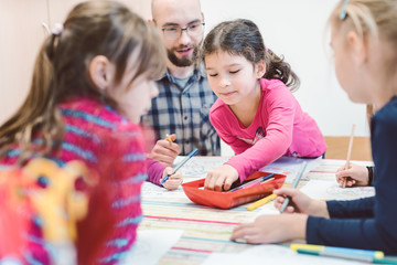 Male Kindergarten teacher with his group of children