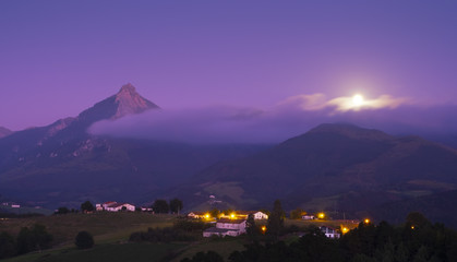 Dusk with a full moon in Lazkaomendi with the Sierra de Aralar and Mount Txindoki in the background.