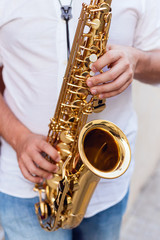 Close up of a man passionately playing the saxophone at the door of a building on the street