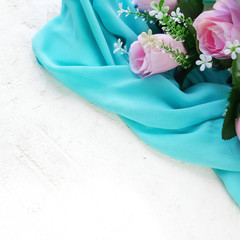 Pink roses with blue soft silk on white textured background. Pretty wedding or celebration decorative concept. Selective focus. Copyspace.
