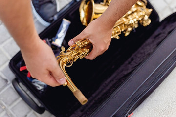 Close up of a man keeping his saxophone on a case on the street