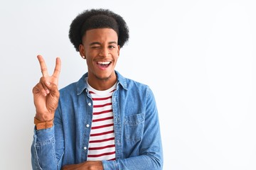 African american man wearing striped t-shirt and denim jacket over isolated white background smiling with happy face winking at the camera doing victory sign. Number two.
