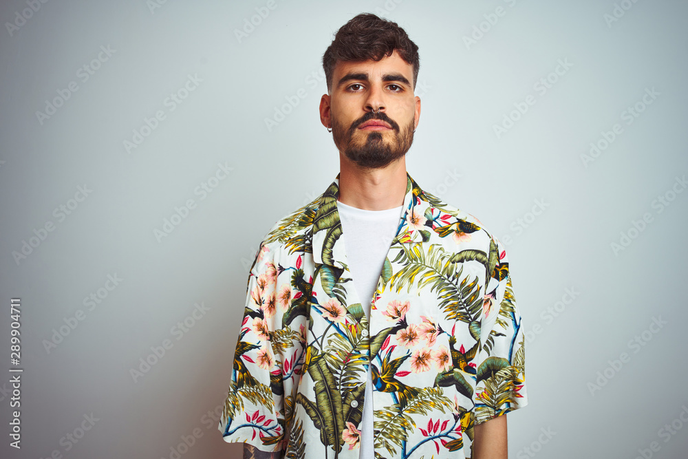 Sticker man with tattoo on vacation wearing summer shirt standing over isolated white background with seriou