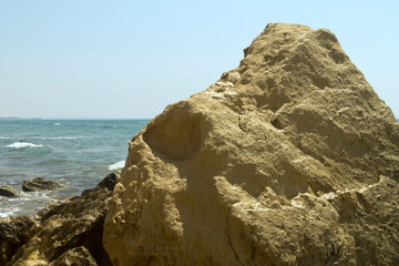 Fototapeta na wymiar Yellow rock in front of blue sea and sky