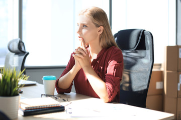 Obraz premium Pensive business woman is keeping hands clasped while sitting in modern office