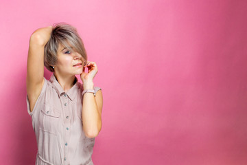 Portrait of young romantic woman with tender smile wearing casual outfit in pastel colors over pink background