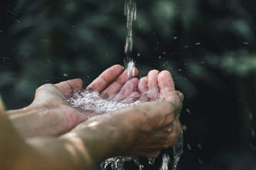 closeup water flow to hand of women for nature concept on the garden background.