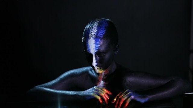Body art portrait of a dark-skinned glowing girl with color make-up