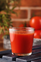 Tasty Tomato juice in a glass with ripe red tomatoes.