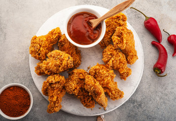 Spicy chicken wings breaded with spices and ketchup on the table.