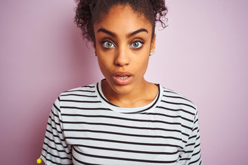 African american woman wearing navy striped t-shirt standing over isolated pink background scared in shock with a surprise face, afraid and excited with fear expression