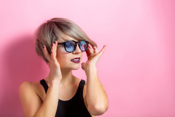 Fashion beautiful young woman with short hair and sunglasses over pink background