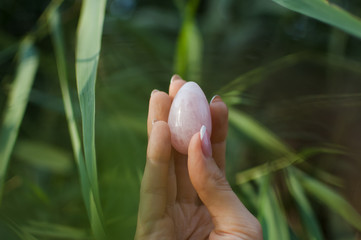 Female hand with french manicure holding pink quartz pink yoni egg for vumfit, imbuilding or...