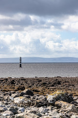 Fototapeta na wymiar Lighthouse in Galway bay with rainy cloud and burren mountains in background