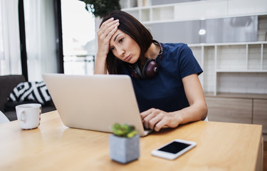 Tired and exhausted middle age female freelancer is working and at her home. Modern living room in background. Freelancing job concept.