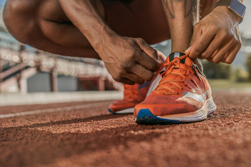 Close up shot of hands tying shoelaces sneaker on the running track. Getting ready to jogging. - obrazy, fototapety, plakaty
