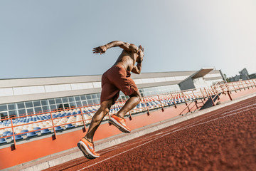 Rear view of an athlete starting his sprint on an all-weather running track