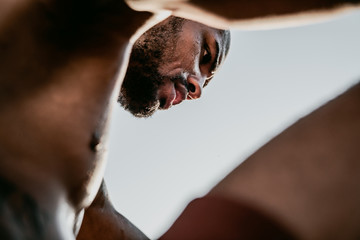 Low angle portrait of sweaty african runner resting after workout outdoor