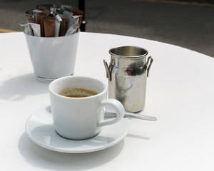 Cup of coffee, cream and sugar on a table in a cafe.