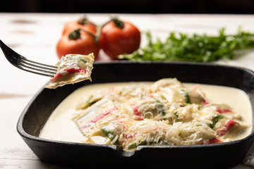 Handmade color ravioli pasta; Multi-colored ravioli pasta in a black iron pan, on wooden white table background.