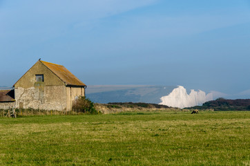 A farm building overlooking distant Seven Sisters White Cliffs at the South Downs, East Sussex,...