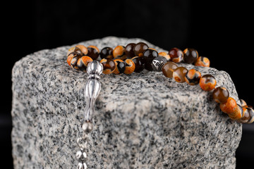 Prayer beads on black background. Close-up Rosary on granite stone