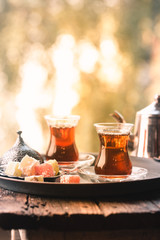 Glass Cup of turkish tea served in traditional style with summer outdore view